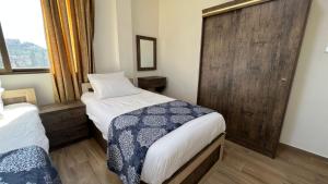 a small bedroom with two beds and a wooden door at Al-jabal castle Hotel - Ajloun in Ajloun