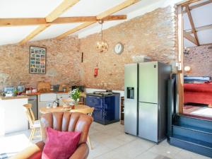 a kitchen with a refrigerator and a table at Parish Land Barn in Spaxton