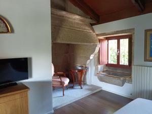 a living room with a stone fireplace and a television at Casa das Capelas in Villamarín