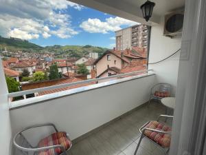a balcony with chairs and a view of a city at ASKonak Apartman Novi Pazar Centar in Novi Pazar