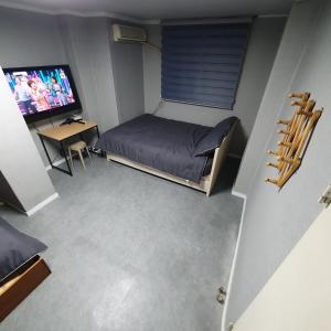 a small room with a bed and a television at Seven Hostel in Seoul