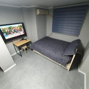 a bedroom with a bed and a desk and a television at Seven Hostel in Seoul
