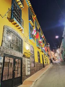 a yellow building with flags on a street at night at Casa CarpeDM in Quito