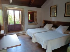 VillamarínにあるCasa das Capelasのベッド2台、窓、ドアが備わる客室です。
