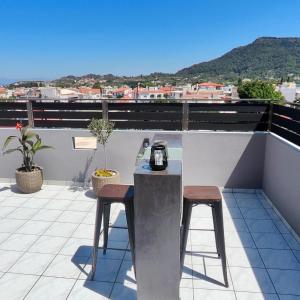 a balcony with a table and stools on a roof at Stamatina's Luxury Penthouse in Pastida in Pastida