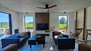 sala de estar con sofás azules y TV de pantalla plana en Moere Dijk, en Koekelare
