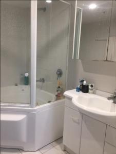 a white bathroom with a tub and a sink at Cozy Room in 2-Room Central Apartment-1 in Canberra