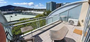 balkon z 2 krzesłami i widokiem na miasto w obiekcie Cozy Room in 2-Room Central Apartment-1 w mieście Canberra