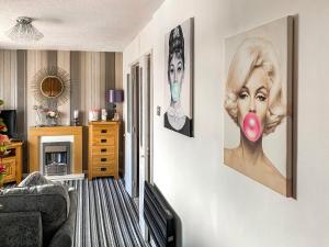 a living room with paintings of a woman on the wall at Sunny Rhyl Apartment - Uk44631 in Rhyl