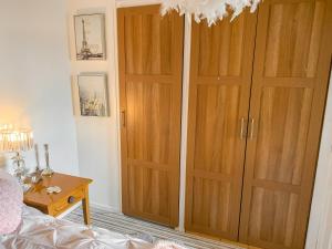 1 dormitorio con armarios de madera, 1 cama y 1 mesa en Sunny Rhyl Apartment - Uk44631, en Rhyl