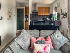 a living room with a couch with pillows and a kitchen at Sunny Rhyl Apartment - Uk44631 in Rhyl