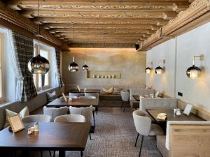 un restaurante con techos de madera, mesas y sillas en Boutique Hotel Montanara B&B en Ischgl