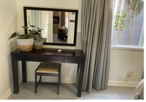 una scrivania con specchio e sedia in camera di Nonna's Cottage a Durban