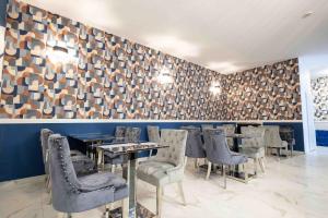 a restaurant with chairs and tables and a wall at Hôtel Center Saint-Quentin in Saint-Quentin