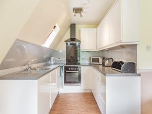 a kitchen with white cabinets and a sink at Gorse Lodge - Uk7050 in Glenurguhart