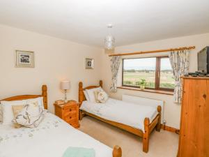 a bedroom with two beds and a window at 2 Stud Cottage in Hainford