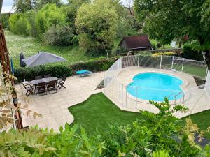 einen Hinterhof mit einem Pool, einem Tisch und einem Sonnenschirm in der Unterkunft La Grange Du Noyer in Cornac