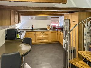 cocina con armarios de madera y mesa en Three Peak Cottage, en Horton in Ribblesdale