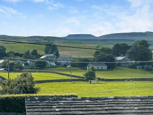 a field of green grass with houses and mountains in the background at Three Peak Cottage in Horton in Ribblesdale