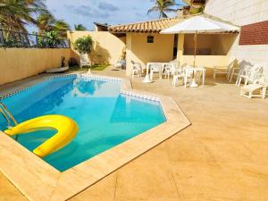 uma piscina com uma piscina de massa amarela em frente a uma casa em Pé na areia do Flamengo em Salvador