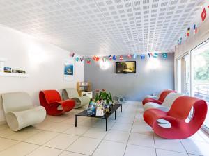 - une salle d'attente avec des chaises rouges et une table dans l'établissement Vacancéole - Les Chambres de la Baie, à Roz-sur-Couesnon