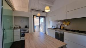 uma cozinha com armários brancos e um balcão de madeira em ATTICO Rimini Centro - Palacongressi em Rimini
