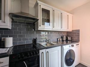 a kitchen with white cabinets and a sink and a dishwasher at Conegra Road by Wycombe Apartments in High Wycombe
