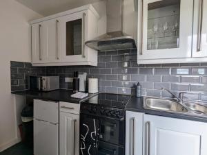 a kitchen with white cabinets and black appliances at Conegra Road by Wycombe Apartments in High Wycombe