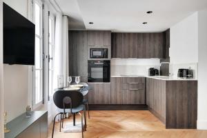 een keuken met houten kasten en een tafel en stoelen bij Brand New Modern Studio in Central Paris - 2P - B1 in Parijs