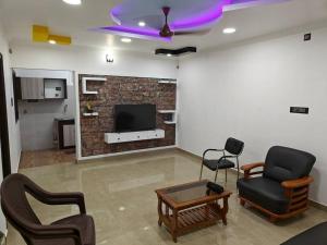 a living room with two chairs and a tv at Treva Pent House in Karaikal