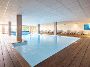 a large swimming pool with blue water in a building at Vacancéole - Les Chambres de la Baie in Roz-sur-Couesnon