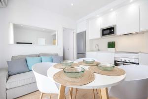 a white kitchen with a white table with bowls on it at APARTAMENTOS CARMEN in Maro