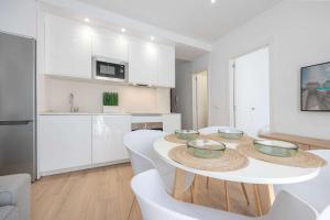 a white kitchen with a table with bowls on it at APARTAMENTOS CARMEN in Maro