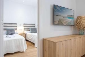 a room with two beds and a tv on the wall at APARTAMENTOS CARMEN in Maro