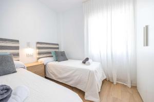 a white room with two beds and a window at APARTAMENTOS CARMEN in Maro
