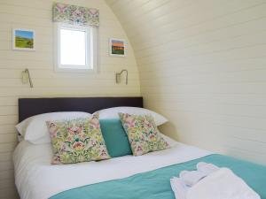 Cama en habitación pequeña con ventana en Efyrnwy Pod Vip, en Llanfyllin