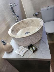 La salle de bains est pourvue d'un lavabo en pierre et de toilettes. dans l'établissement Small luxury apartment, à Anavyssos