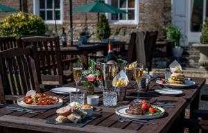 una mesa de madera con platos de comida y copas de vino en Chilston Park Hotel en Maidstone