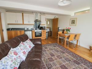 a living room with a couch and a kitchen at Plum Hill Apartment in Oswestry