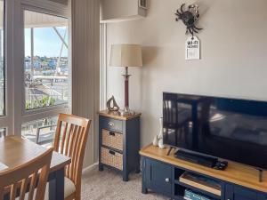 a living room with a television and a dining room table at 3 Linden Court in Brixham