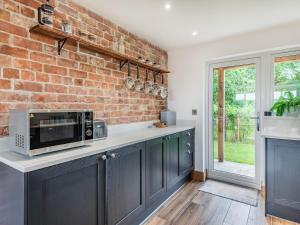 a kitchen with blue cabinets and a brick wall at Dragonfly Den - Uk44530 in Horncastle