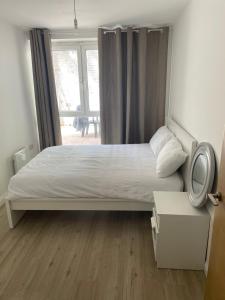 a bedroom with a white bed with a window at Mac-Stephneil Holiday Homes in London