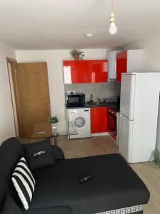 a living room with a couch and a kitchen with red cabinets at Mac-Stephneil Holiday Homes in London