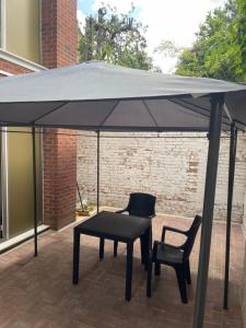 a black umbrella on a patio with two chairs and a table at Mac-Stephneil Holiday Homes in London