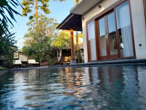 a swimming pool in front of a house at Tropical Retreat Villa in Gianyar