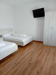 Dieses weiße Zimmer verfügt über 2 Betten und einen Flachbild-TV. in der Unterkunft Gura Raului Casa de Vacanta in Gura Râului