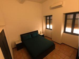 a bedroom with a green bed and two windows at Casa na Vila T2 in Fuzeta