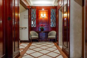 - un couloir avec deux chaises et une table fleurie dans l'établissement Lancaster Hotel by Castelo Itaipava, à Curitiba
