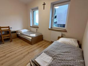 1 dormitorio con 2 camas y una cruz en la pared en Karmelitański Dom Gościnny, en Zawoja