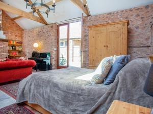 a bedroom with a bed and a brick wall at Parish Land Barn in Spaxton